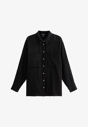 Chemise noire à manches longues et à boutons, fabriquée en tissu texturé. Présente un col, deux poches avant et des détails en boutons en bois.