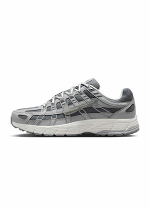 Baskets Nike P-6000 grises et blanches avec une tige en mesh et des superpositions synthétiques en couches, montrées de profil sur fond blanc.