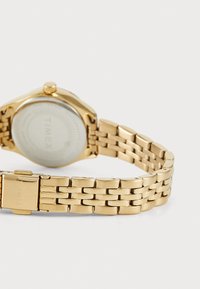 Montre en métal doré avec un boîtier rond et une finition polie, dotée d'un cadran blanc et d'un bracelet à maillons. Inscription sur le fermoir.