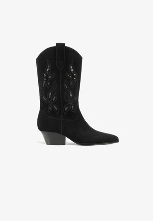 Botte de cowboy mi-mollet en daim noir avec bout pointu, talon incliné et broderie florale ajourée sur la tige.