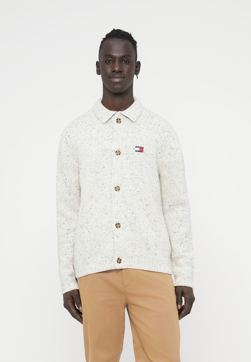 Πλεκτή κρεμ ζακέτα με υφή με στίγματα, με κουμπιά μπροστά και μυτερό γιακά. Διαθέτει μικρό λογότυπο και κουμπιά σε αντίθετο χρώμα.