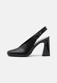 Czarne buty na obcasie typu slingback z kwadratowym noskiem, z lakierowanym wykończeniem i metalowym pierścieniem na pasku. Górna część z teksturowanej skóry.