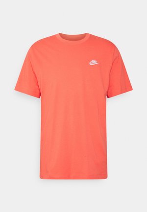 Camiseta de algodón color coral con cuello redondo, mangas cortas y un logotipo blanco de Nike en el lado izquierdo del pecho. Textura suave y ajuste estándar.