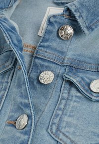 Lichtblauwe denimjack met zilverkleurige metalen knopen, zichtbare stiknaadaccenten en een klassiek col ontwerp met twee voorzakken.