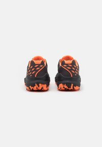 Black running shoes with orange accents, textured rubber sole, and multiple cut-out patterns on the sides for breathability and support.