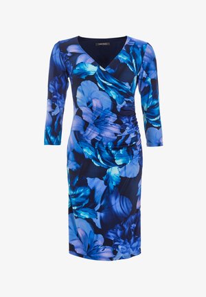 Bloemenjurk met een marineblauwe achtergrond, voorzien van blauw en paarse bloemenpatronen, v-hals en lange mouwen. Gerimpeld detail aan de zijkant.