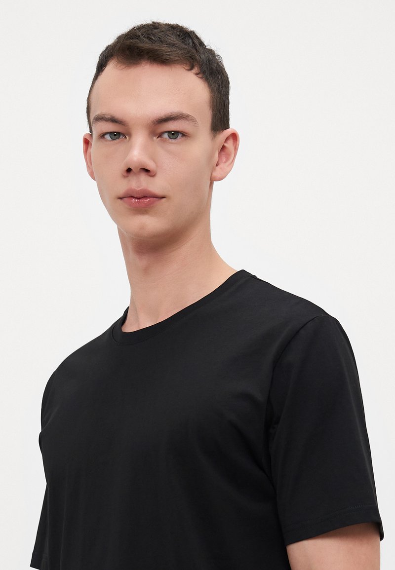 Zwarte T-shirt van katoenmix, met een ronde hals en korte mouwen, voorzien van een zachte textuur en een aangesloten ontwerp.