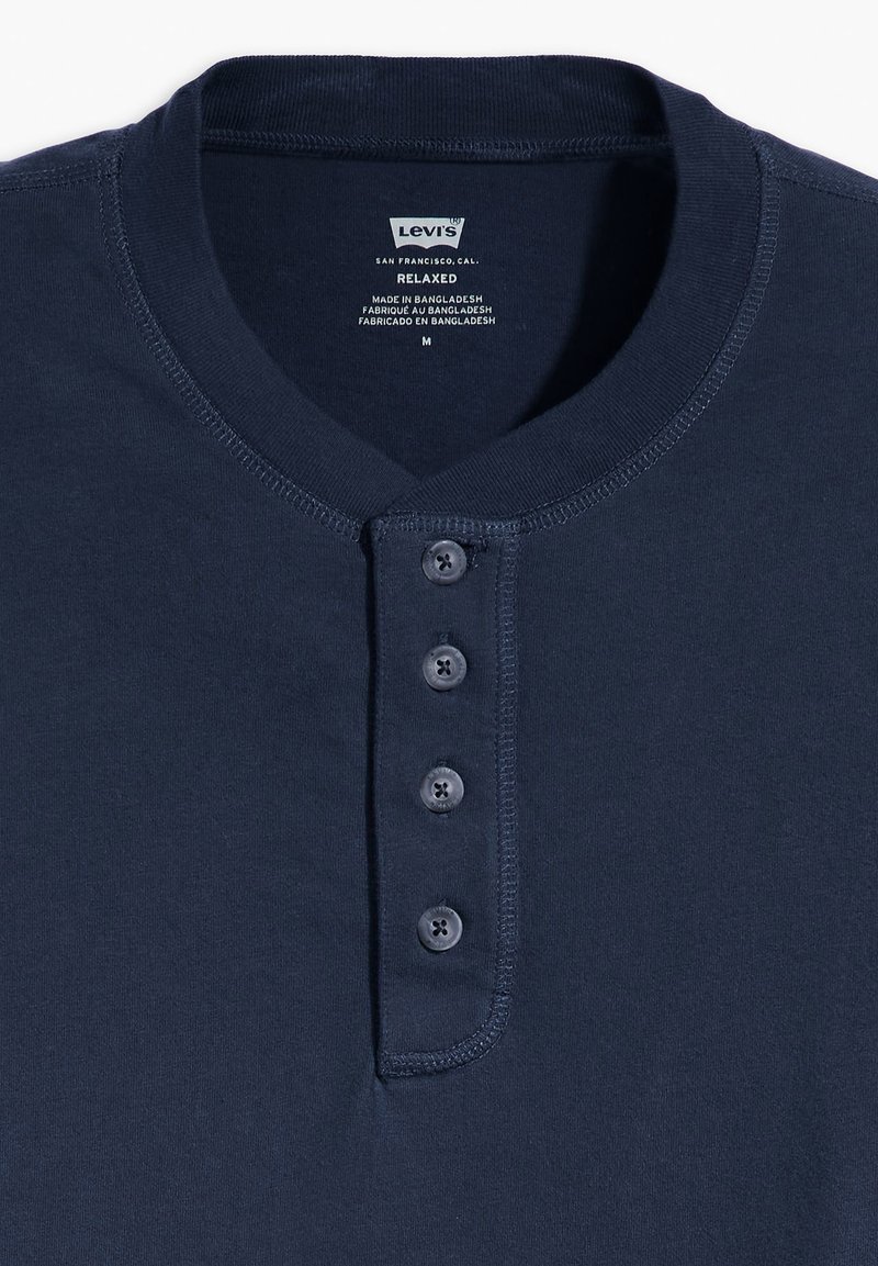 Maglietta henley blu navy realizzata in tessuto morbido, con colletto rotondo, placca con cinque bottoni e dettagli di orlo cuciti. Taglia M.