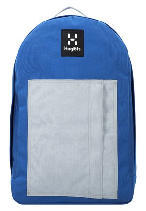 Blue fabric backpack with a gray front pocket, curved top, and a logo patch in black. Features a sturdy design and reinforced stitching.