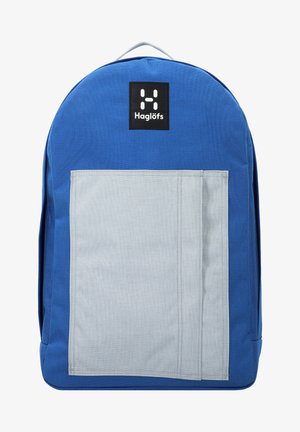 Zaino di tessuto blu con una tasca anteriore grigia, parte superiore arrotondata e un'etichetta con logo nera. Presenta un design robusto e cuciture rinforzate.