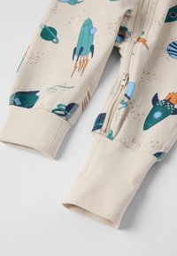 Beiger Zip-Jumpsuit mit bunten Raketen- und Planetenmustern, elastischen Bündchen und einer glatten Baumwollbeschaffenheit.