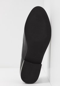 Semelle de chaussure noire avec surface en caoutchouc texturé, présentant une forme arrondie et une indication de taille 37 au talon.