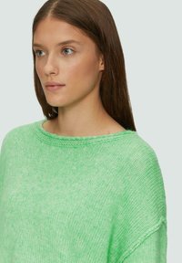 Hellgrüner Strickpullover mit weitem Ausschnitt, lockerer Passform und strukturierter Oberfläche mit dezenten Farbvariationen.
