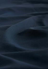 Tissu bleu marine avec une texture côtelée, présentant des plis doux qui créent profondeur et dimension, mettant en valeur une surface uniforme et lisse.