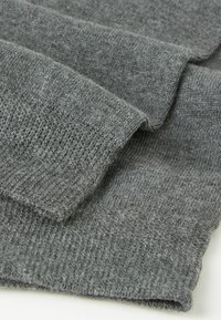 Grå stickad tyg med en mjuk textur; har ett ribbat mönster och släta kanter, som visar överlappande lager.