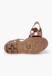 Brown plastic sandals with chunky, ridged sole. Strappy design with a back heel support and side buckle for adjustable fit.