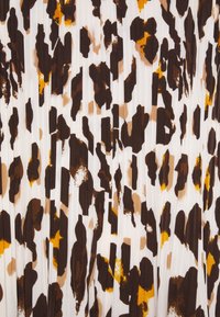 Skládaná látka s bílým pozadím zdobená leopardím vzorem v hnědých, béžových a oranžových odstínech, vykazující různé textury a tvary.