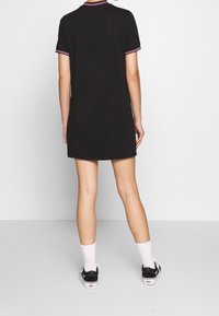 Robe courte noire à manches courtes, avec un col et des poignets à motifs roses, confectionnée dans un tissu doux, à coupe décontractée et longueur jusqu'au genou.