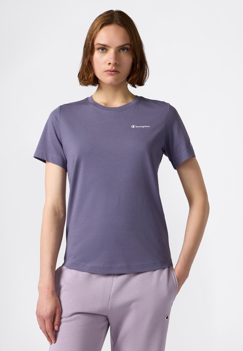 T-shirt corto a maniche corte di colore lilla chiaro, realizzato in tessuto liscio, con un piccolo logo bianco sul petto sinistro. Design classico con scollatura a girocollo.