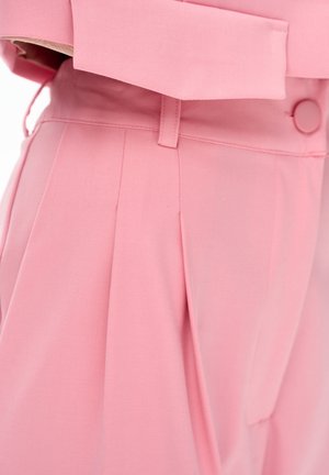 Różowe spodnie z wysokim stanem, plisami, szlufkami na pasek i dopasowanym różowym zapięciem na guzik w talii.