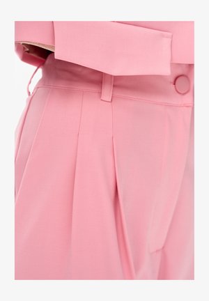Różowe spodnie z wysokim stanem, plisami, szlufkami na pasek i dopasowanym różowym zapięciem na guzik w talii.