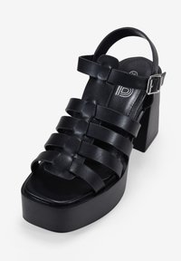 Black platform sandals with wide cross-strap design, adjustable ankle strap, and block heel. Made of smooth leather with a sturdy finish.