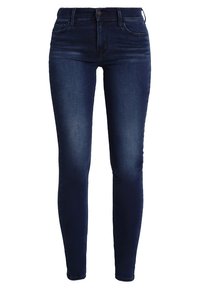 Jeans skinny azul oscuro con detalles desgastados en los muslos, cierre de botón y cremallera en el frente, y diseño de cinco bolsillos.