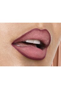Rouge à lèvres mauve mat appliqué sur des lèvres pleines, avec une texture lisse et un contour légèrement plus foncé. La peau est légèrement illuminée en arrière-plan.
