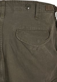 Szorty bawełniane w kolorze oliwkowym z tylną kieszenią z zaokrągloną klapą, zapięciem na metalowy guzik oraz podwójnymi szwami dla większej trwałości.