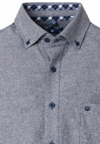 Koszula zapinana na guziki w jasnoszarym materiale w jodełkę. Posiada granatowy wzór w kratkę wewnątrz kołnierza oraz dwa granatowe guziki na listwie.