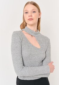 Jasnoszary sweter prążkowany z wysokim kołnierzem i bocznym wycięciem. Długie rękawy z dopasowanymi mankietami. Miła w dotyku faktura, dopasowany krój.