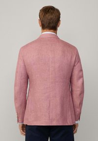 Blazer de lino rosa claro con un corte estructurado, solapas en pico y aberturas laterales. Textura suave con detalles de botones en los puños.