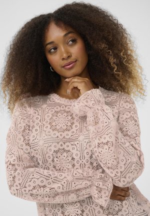 Pink lace blouse with floral embroidery, long sleeves, and a scalloped neckline featuring intricate cut-out patterns and soft texture.