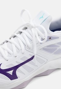 Pantof cu model sport de culoare albă, dotat cu un superior din plasă respirabilă, cu accente violet, sireturi și o talpă texturată pentru aderență.