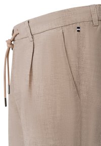 Beige, strukturierte Hose mit gebundenem Kordelzugbund, vorderen Falten und einem kleinen dekorativen Streifenakzent in drei Farben an der Seite.