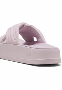 Sandales à plateforme roses avec des brides matelassées, texture douce et forme arrondie. Présente le logo Puma sur le côté et une semelle intérieure rembourrée pour le confort.
