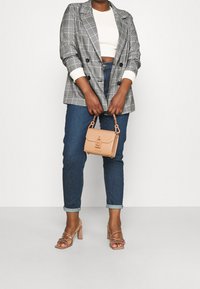 Grå rutig dubbelknäppt kavaj med vita manschetter, tillsammans med uppkavlade mörkblå jeans, snöriga beige klackar och en liten beige handväska.