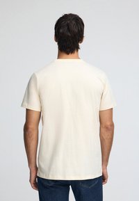 Ljusgul bomulls-t-shirt med korta ärmar, standard rund halsringning och en slät textur. Enkel design, inga synliga mönster eller accenter.