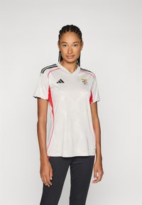Grijze sporttrui met zwarte en rode accenten, korte mouwen, V-halsontwerp, met een getextureerd patroon en clublogo op de borst.