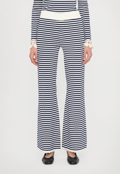 Hosen in Navy und Weiß mit Streifen, ausgestellter Form, aus strukturiertem Stoff, elastischem Bund und gewelltem Spitzenbesatz am Saum. Getragen mit schwarzen Schuhen.
