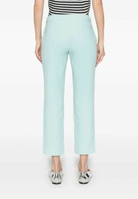 Pantaloni verde menta chiaro con un taglio dritto e una texture liscia, dotati di una vita standard e calzature argentate visibili sotto.
