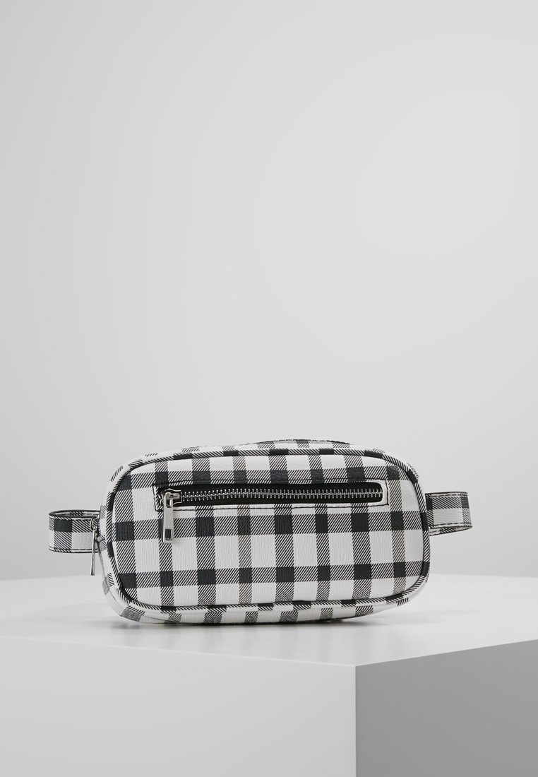Sac à damier noir et blanc de forme rectangulaire, fabriqué en matériau texturé, avec une fermeture éclair à l'avant et une poignée latérale.
