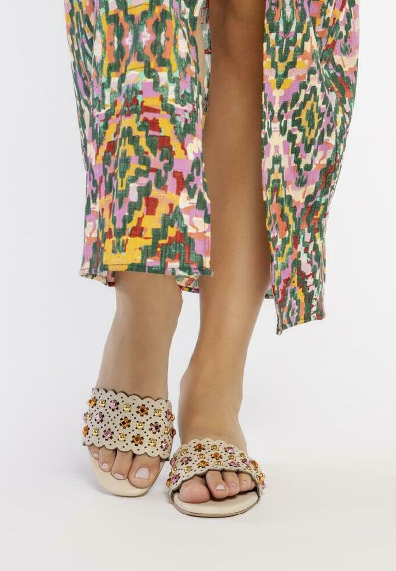 Las sandalias de diapositiva beige presentan recortes florales y adornos coloridos. La parte superior tiene un diseño ondulado con una suela lisa, ofreciendo un diseño casual.