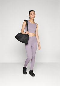 Lavender ribbed crop top and matching leggings paired with a black duffel bag. The outfit features a fitted design and textured fabric.