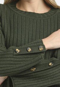 Ciemnozielony sweter dziany w prążki, z okrągłym dekoltem i ozdobnymi guzikami na rękawach. Guziki są okrągłe, z matowym wykończeniem.