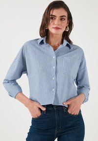 Blue and white striped button-up shirt, long sleeves, chest pocket, relaxed fit, made from lightweight fabric with a smooth texture.