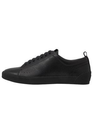 Czarny niski skórzany sneaker z teksturowaną powierzchnią, czarnymi sznurowadłami, gumową podeszwą i pętlą na pięcie, widoczny z profilu.