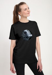 Svart t-shirt med motiv av Dödens Stjärna i grå nyanser med vita prickar som liknar stjärnor. Kort ärm, rund halsringning.