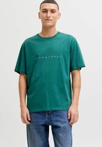 Groen katoenen t-shirt met korte mouwen en een ronde hals. Heeft witte, gedrukt tekst "JACK & JONES" over de borst in een minimalistische stijl.