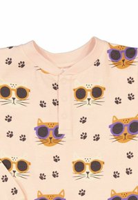 Pyjamatopp i mjuk rosa tyg med mönster av tecknade katter med solglasögon och tassavtryck. Henley-krage med tre knappar.
